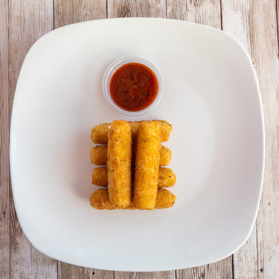 Golden-brown mozzarella sticks stacked on a white plate with a side of marinara sauce.